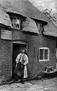 En mand, der ryger pibe uden for en butik, Worcestershire, c1922. af A. W. Cutler