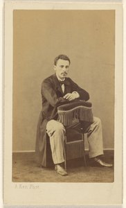 [Mand med overskæg, siddende, med fronten mod ryggen på en stol med frynser]. af Alexandre Ken