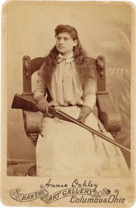 Annie Oakley: Annie Oakley:. Her sidder den legendariske skarpskytter temmelig nedslående i en massiv stol i renæssancestil, et haglgevær hviler i hendes skød. Hendes sarte feminine træk og strømmende hår modsiger hendes robuste udendørsbillede ©Buyenlarge af American Photographer