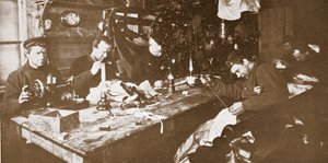 I hytten midt om vinteren beskæftigede mændene sig med at sy pels til tøj, der skulle bruges i forårets kælkning, pub. London 1907 (s/h-billede) af Anthony Fiala