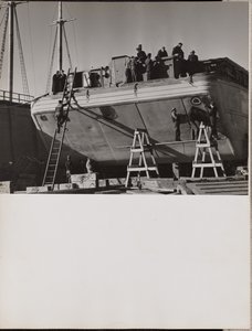 [En gruppe mænd arbejder på en båd i havn].
