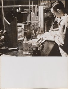 [En mand i et laboratorium bruger begge hænder til at placere en stor pipette i et bægerglas]. af Arnold Eagle