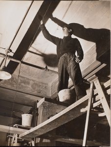 [En mand står på et træstillads og maler et loft]. af Arnold Eagle