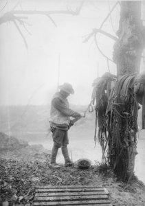 En uidentificeret australsk artillerifører renser mudder fra sit holds seletøj i en billet nær Mametz, december 1916 af Australian Photographer