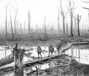 Fem australiere, medlemmer af en feltartilleribrigade, der passerer ad en duckboard-bane over mudder og vand blandt magre, nøgne træstammer i det ødelagte Chateau Wood, en del af en af stridsmændene af Australian Photographer