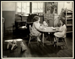 To blinde synshandicappede piger spiser ved et lille bord med en dukke hos New York Association for the Blind, 111 East 59th Street, New York, 1933 (sølv gelatinetryk)