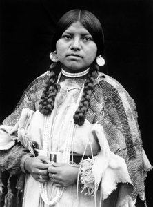 Cayuse kvinde, halvlangt portræt, stående, vendende front, fletninger, shell disk øreringe, shell perle choker og shell perler om halsen, perlebehandlet buckskin kjole med perlebælte ca. 1910, foto Edward S. Curtis af Edward Sheriff Curtis