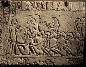 En gruppe negroide fanger omgivet af vagter bevæbnet med køller, mens en skriver udfærdiger en rapport, relief fra Horemhebs grav i Saqqara af Egyptian 18th Dynasty