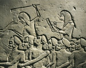 En gruppe negroide fanger omgivet af vagter bevæbnet med køller, mens en skriver udfærdiger en rapport. Relief fra Horemhebs grav i Saqqara, detalje af Egyptian 18th Dynasty
