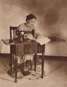 Husmor arbejder på symaskinen, midt i 1930