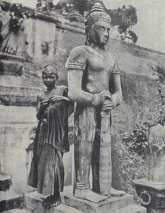 Ung buddhistisk nybegyndermunk ved siden af en statue af Buddha, Fransk Indokina (s/h-billede)