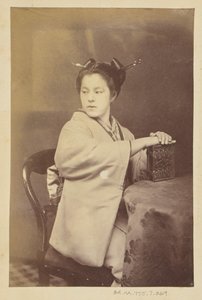 [Siddende japansk kvinde med et cartes-de-visite-album ved et bord]. af Felice Beato
