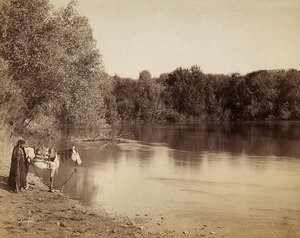 En mand i traditionel kjole med sin hest, foran en sø i Egypten af Félix Bonfils