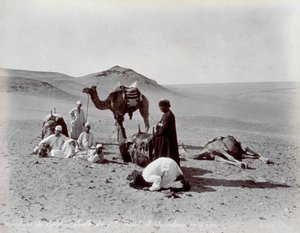 Egyptiske camelere under en pause i ørkenen. I forgrunden ser to medlemmer af den lille gruppe ud til at bede.