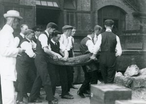 Et hold mænd bærer en alligator, der overvåges af Sir Peter Chalmers Mitchell, London Zoo, 1924 af Frederick William Bond