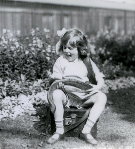 En ung pige Betty holder en østlig indigo slange, mens hun sidder på en læderstamme, London Zoo, 1924 af Frederick William Bond