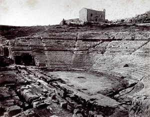 Resterne af det græske teater i Siracusa i Neàpolls monumentale park. I forgrunden det halvcirkelformede orkester og caveaen af Giorgio Sommer