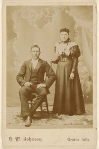 [Uidentificeret par: mand med overskæg siddende, kvinde stående]. af H. M. Johnson
