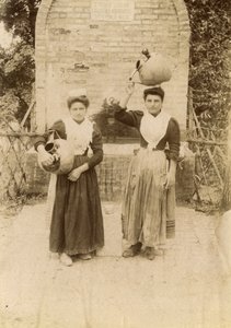 To unge kvinder iført traditionelt tøj og med terrakottakrukker nær en brønd, Marche, Italien, ca. 1910 af Italian Photographer