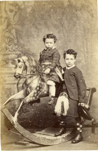 Ung pige på gyngehest med ung dreng i kilt stående, 1860
