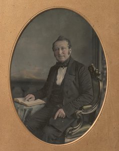 Siddende mand peger på en passage i en åben bog, 1850