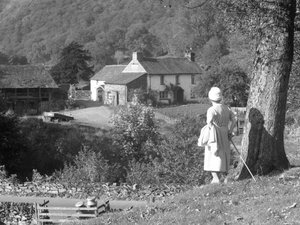 En kvinde står ved siden af et træ med ryggen til kameraet og kigger ud mod Yew Tree Farm. af Joseph Hardman