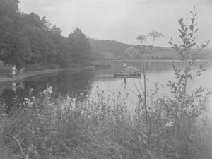Mand fisker i en båd på Estwaite Water og to piger i vandkanten