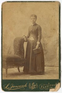 Fotografi af en kvinde, der står ved siden af en stol og holder en bog, slutningen af det 19. århundrede. af Louis Janousek