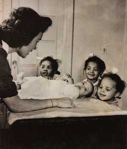 Sygeplejerske Henry Street hjælper tre afroamerikanske piger i Harlem, New York City. af Luigi Leoni