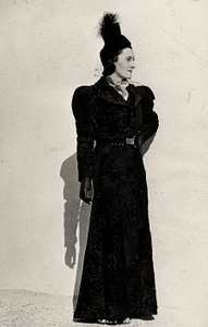 Model præsenterer en artikel skabt af det italienske couture-hus "Cicogna" bestående af en breitschwanz-overfrakke samlet i taljen af et bælte med juvelspænde, suppleret med en lille plumeret hat med slør (s/h-foto)