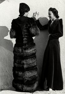 To modeller præsenterer kreationer af det italienske couture-hus "Dragoni". Den ene model set bagfra bærer en sølvrævefrakke. Den anden model er iført en lang fløjlsoverfrakke. (s/h foto)