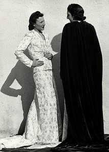 To modeller præsenterer kreationer af det italienske couture-hus "Dragoni". Den ene model bærer et outfit i blemateriale bestående af en jakke og lang nederdel med tog. Den anden model, set bagfra, bærer en lang fløjlskappe. (s/h foto) af Luis Bogino