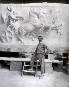 Portræt i fuld længde af den berømte billedhugger Pietro Canonica. Han poserer i sit studie foran et marmorhøjrelief, han arbejder på (s/h-foto)