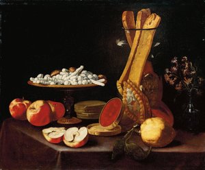 Slik på en tazza, narcissi i en glasvase, brødstænger i en krukke og æbler, gelé og en citron på et draperet bord