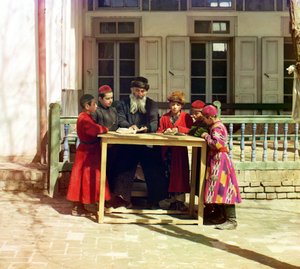 En gruppe jødiske børn med en lærer på et bord foran et hus, Samarkand, det russiske imperium, mellem 1905 og 1915