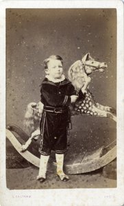 Ung dreng stående ved en gyngehest af Silas Eastham