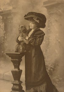 [Sarah Bernhardt står i et atelier og holder en lille sort hund på en udsmykket, udskåret træpiedestal]. af Theodore C. Marceau
