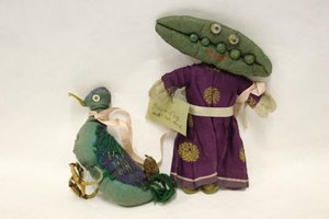 Miss Green Peas kludedukke, hovedet er formet som en ærtebælg, og hun fører sin kæledyrsand i et lyserødt satinbånd af Una Maw