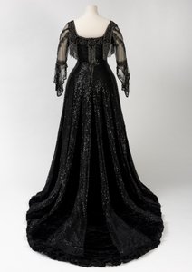 Sort aftenkjole i fuld længde båret af dronning Alexandra, med dekoration af perler og pailletter og inkorporeret dronning Alexandras signaturnavnebånd i sort silke og guld, lavet af Barolet fra Knightsbridge, London 1908-1910 (silke og fløjl) af Unbekannt
