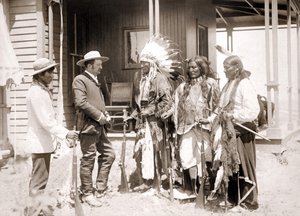 Tre cheyennere klædt i ceremonielle kostumer og iført våben hilser på en hvid ledsaget af en tolk. sd. slutningen af det 19. århundrede af Unknown artist