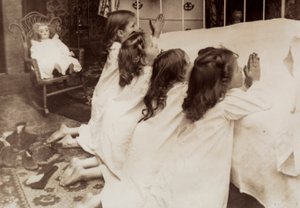 Fire små piger knæler ved siden af en seng, mens de beder deres aftenbøn. af Unknown photographer