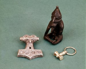 Amuletter af vikingeguder: i forgrunden to små sølvhammere, der symboliserer guden Thor. Statuetten repræsenterer Freyr, frugtbarhedsguden. Historisk museum i Stockholm, Sverige.