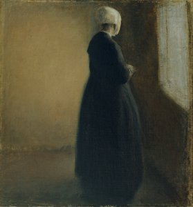 En gammel kvinde, der står ved et vindue
