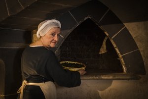 Historisk genopførelse: Tjenestepige sætter kage i ovnen i køkkenet på slottet af John Ward Dunsmore