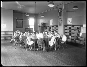 Børn lytter til en kvinde i læsesalen i en uidentificeret afdeling af Queens Borough Public Library, ca. 1910 (s/h-foto) af William Davis Hassler