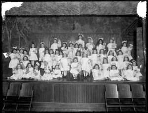 En gruppe små piger poserede på en lille scene med dukker, sandsynligvis det romersk-katolske forældreløse asyl, Kingsbridge, Bronx, ca. 1911