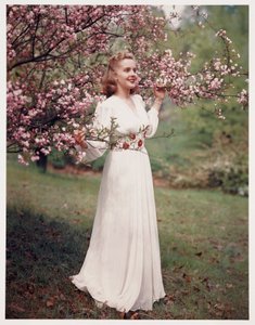 Kvinde modellerer en kjole nær blomstringen, ca 1940