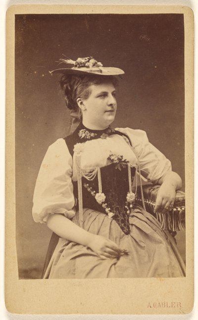 [Uidentificeret kvinde i indianerkostume med hat, siddende]. af A. Gabler