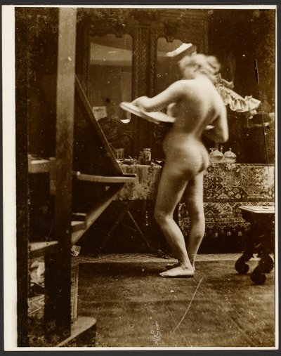[Kvindelig nøgenmodel står i et studie med en skitsebog i hånden]. af Alphonse Maria Mucha