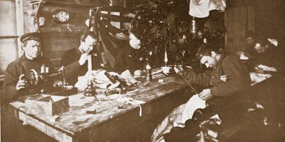 I hytten midt om vinteren beskæftigede mændene sig med at sy pels til tøj, der skulle bruges i forårets kælkning, pub. London 1907 (s/h-billede) af Anthony Fiala